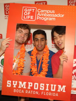 Three Gift of Life Campus Ambassadors, all young men of varied skin tones who are laughing, pose with a selfie frame that says "Gift of Life Campus Ambassador Program". 